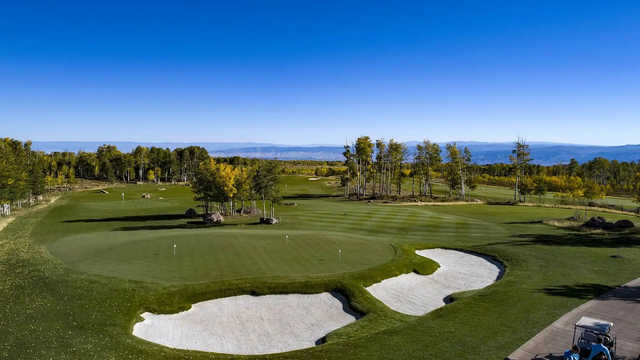 A view of a green and the practice putting green surrounded by bunkers at Cornerstone Club.