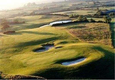 A sunny view of a green guarded by bunkers at Woodspring Golf & Country Club