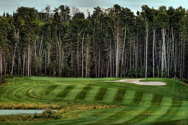A view of a green defended by an undulating bunker and a pond at Elk Ridge Resort