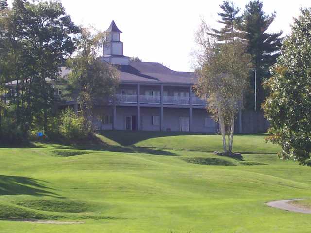A sunny day view of a hole and the clubhouse at Windham Country Club