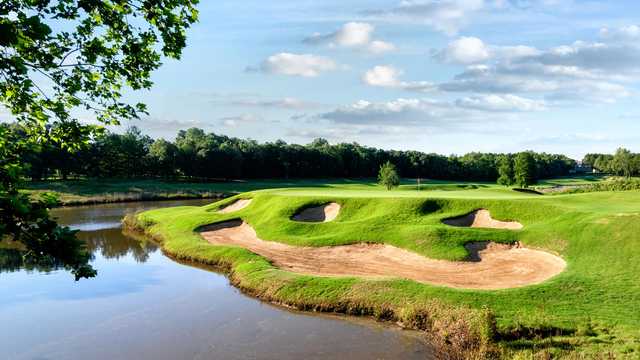 A view of a green with water and bunkers coming into play at The Golf Club of Oklahoma.