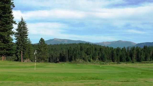 A view of a green and mountains in the distance at Rivers Bend Golf Course