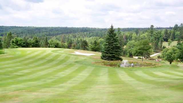 A view of a green protected by a pond and a bunker at Sherwood Golf and Country Club