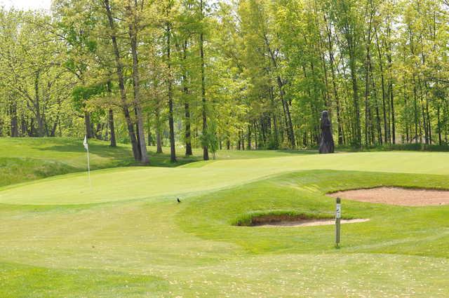 A sunny view of a hole protected by sand traps at Mystic Hills Golf Club