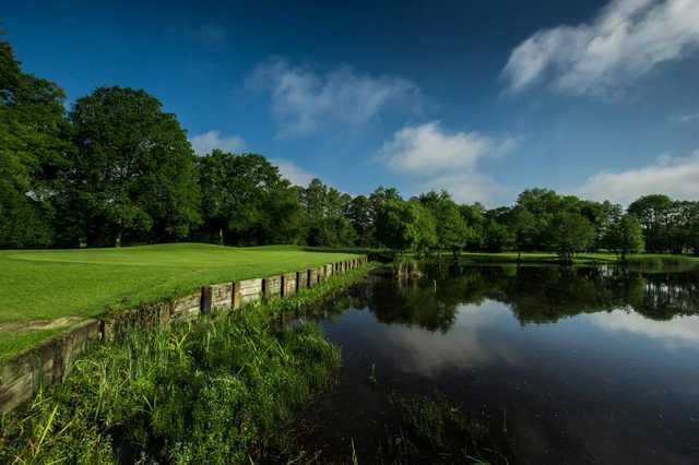 A view of a green with water on the right side at Merrist Wood Golf Club