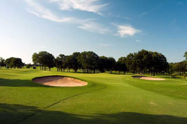 A sunny view of a green flanked by sand traps at KickingBird Golf Club.